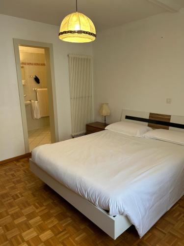 Un dormitorio con una gran cama blanca y una lámpara de araña. en Ristorante Bar Pensione Novaggio en Novaggio