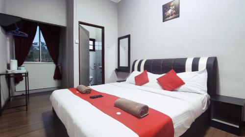 1 dormitorio con 1 cama blanca grande con almohadas rojas en Hotel Rasa Sayang 2 en Tanah Rata