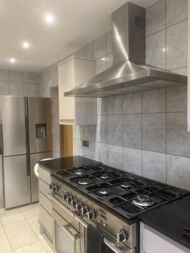 a kitchen with a stove and a stainless steel refrigerator at Private room, renovated with large size white desk In SE9 6PG in London