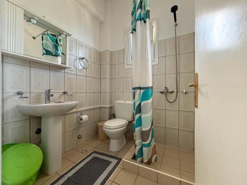 a bathroom with a toilet and a sink and a shower curtain at Imerolia Studios in Kassiopi