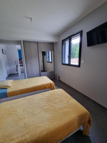 une chambre avec deux lits et une télévision à écran plat dans l'établissement Maison proche du circuit 24h du Mans, à Fay