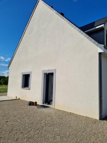 un bâtiment blanc avec une porte sur son côté dans l'établissement Maison proche du circuit 24h du Mans, à Fay