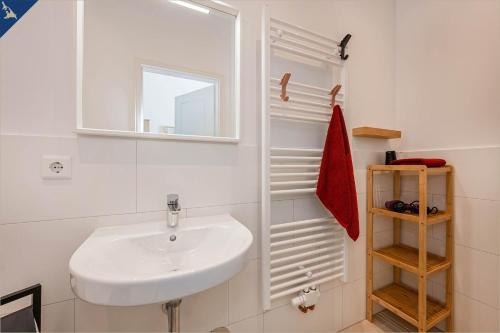 ein weißes Badezimmer mit einem Waschbecken und einem Spiegel in der Unterkunft Apartment Martha 3 in Heringsdorf
