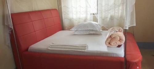 Una cama roja con toallas y un animal de peluche. en BM. Beach hotel at Nansio, Ukerewe island, en Hamukoko