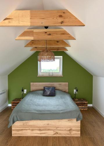a bedroom with a bed with a green wall at Chatka między brzozami nieopodal Wkry in Goławice