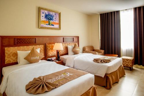 a hotel room with two beds and a chair at Sai Gon Rach Gia Hotel in Rạch Giá