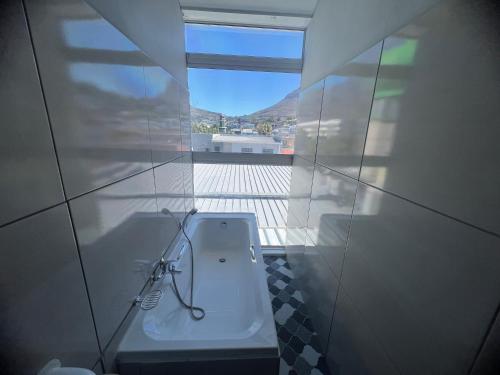 uma casa de banho com um WC branco e uma janela em M & B Backpackers em Cidade do Cabo