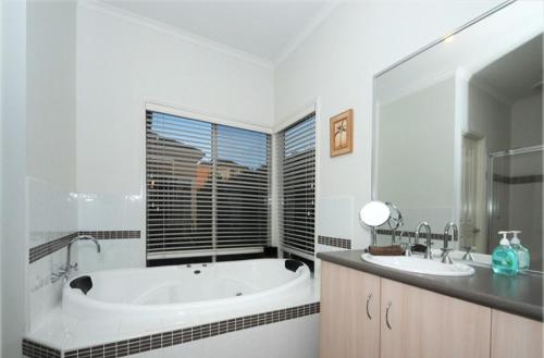 Baño blanco con bañera y lavamanos en House on the Heights, en Lyndhurst
