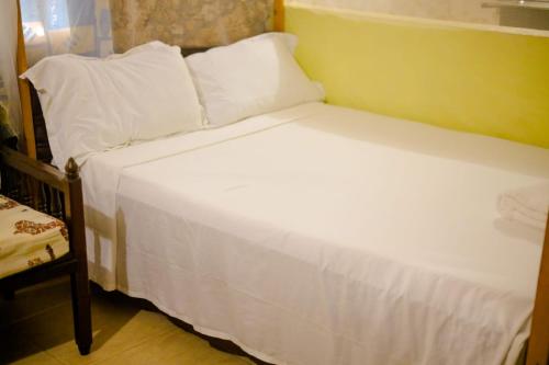 1 cama con sábanas blancas y almohadas en una habitación en Kikambala Eco Villas en Mombasa