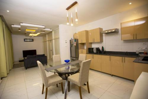 cocina y comedor con mesa de cristal y sillas en Kalinou Niamey, en Niamey