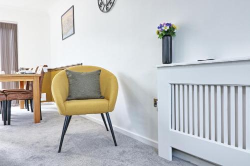 uma cadeira amarela sentada num quarto com um berço em The Only Way is Basildon, close to town, Trade and corporate guests also welcome em Basildon