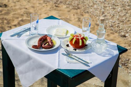 アストリスにあるAstris Beachの白いテーブルクロスの上に食べ物の皿が2枚置かれたテーブル