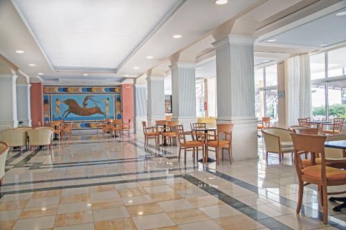 una sala da pranzo con tavoli, sedie e un dipinto di Atlantis Hotel a Città di Kos
