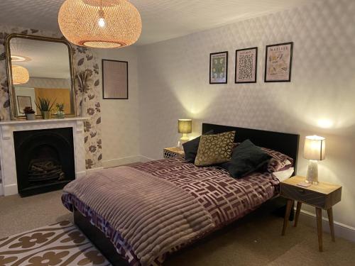Luxury Putney Riverside Apartment في لندن: غرفة نوم بسرير مع موقد ومرآة