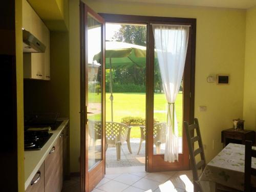 une cuisine avec une porte menant à une terrasse avec un parasol dans l'établissement Elegante Wohnung in der grünen Umgebung des Parks einer venezianischen Villa, à Mira