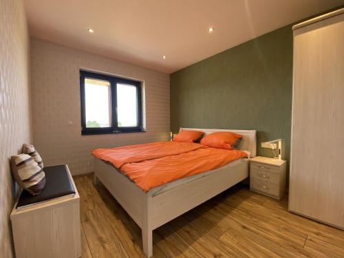 - une chambre avec un lit doté d'oreillers orange et une fenêtre dans l'établissement Ferienwohnung am Weiher - Wohnung 3 - Für 2 Personen, à Nideggen