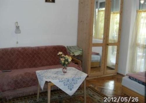 een woonkamer met een bank en een tafel met bloemen bij Wohnung in Bükfürd mit Garten in Bükfürdő