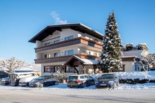 ein großes Gebäude mit Autos im Schnee in der Unterkunft Wohnung in Reith Im Alpbachtal mit Garten und Terrasse in Reith im Alpbachtal