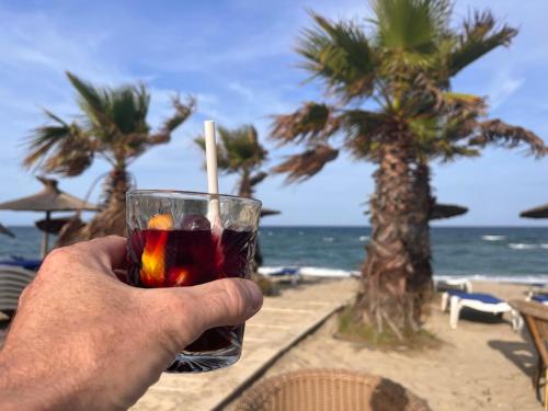 una persona sosteniendo una bebida frente a la playa en Villa T3 6 couchages - Piscine-WIFI-Garage en Saint-Cyprien