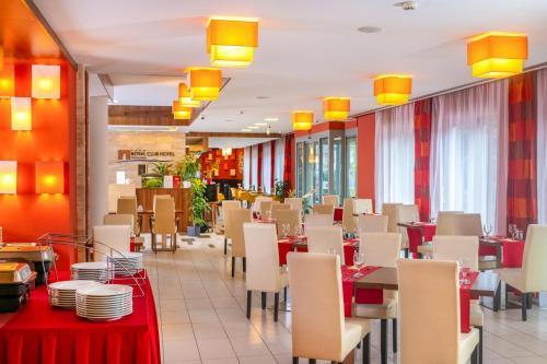 un comedor con mesas, sillas y luces amarillas en Royal Club Hotel, en Visegrád