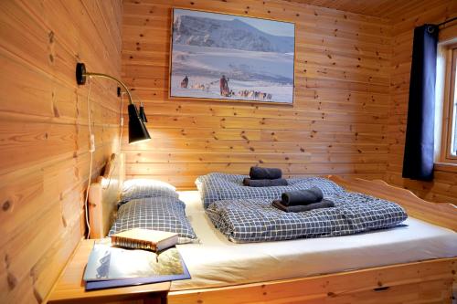 a bedroom with two beds in a wooden wall at Cabin Huskyfarm Innset in Innset
