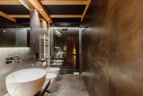 une salle de bains avec trois lavabos et trois toilettes dans l'établissement Au Charmant Petit Lac - Ecohotel Parc & Spa, à Champoluc