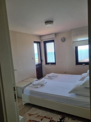 a bedroom with a large white bed with two windows at Villa Elea in Nesebar