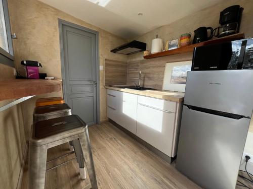 Elle comprend une petite cuisine équipée d'un réfrigérateur blanc et d'un tabouret. dans l'établissement T1 Au pied du Garlaban 30 minutes de Cassis, à Roquevaire