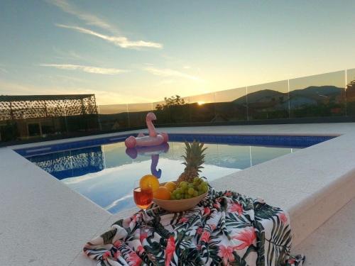 un bol de fruta en una mesa junto a una piscina en wundeschönes Ferienhaus mit eigenem Pool und Meerblick, en Bilice