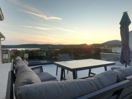 un sofá y una mesa en un balcón con vistas a la puesta de sol en wundeschönes Ferienhaus mit eigenem Pool und Meerblick, en Bilice