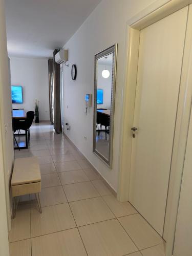 un couloir avec un miroir et une chambre avec une table dans l'établissement White Coast Apartment, à Saranda