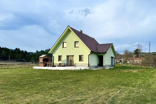 a yellow and green house on a grass field at Tribistovo Holiday House in Posušje