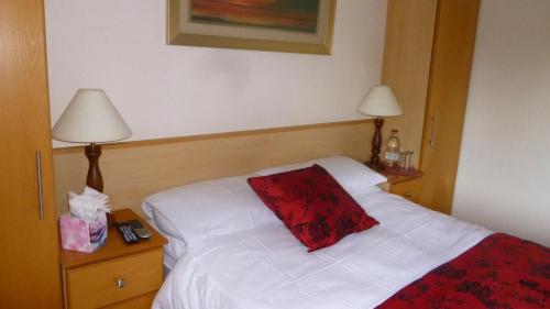 a bedroom with a white bed with a red pillow on it at Corcoran's Lodge in Ferns