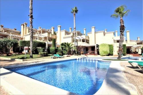 a swimming pool in front of a building with palm trees at La Manga Club Resort - 3 bedroom Duplex - La Colina in Atamaría