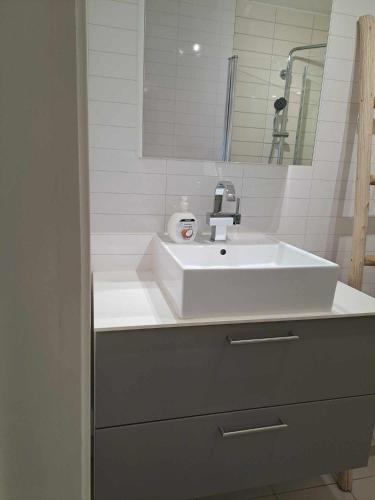 a bathroom with a white sink and a mirror at Apartment Bystranda - City Beach in Kristiansand