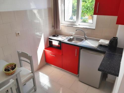a small kitchen with red cabinets and a sink at Villa Maroula in Afantou