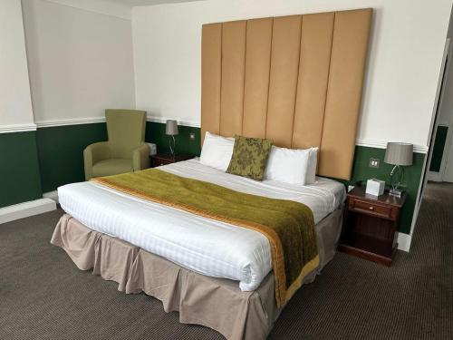 een hotelkamer met een groot bed en een stoel bij Best Western Priory Hotel in Bury Saint Edmunds