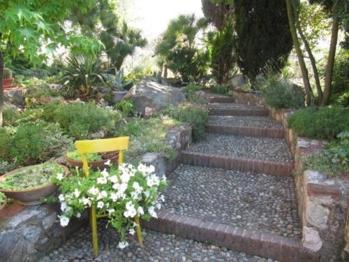 un jardín con escaleras, una silla amarilla y flores en Ferienwohnung für 6 Personen ca 100 qm in Puegnago sul Garda, Gardasee Westufer Gardasee, en Castello