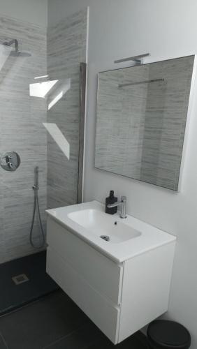 een witte badkamer met een wastafel en een spiegel bij La casa al mare di MatiGiò in Pietra Ligure