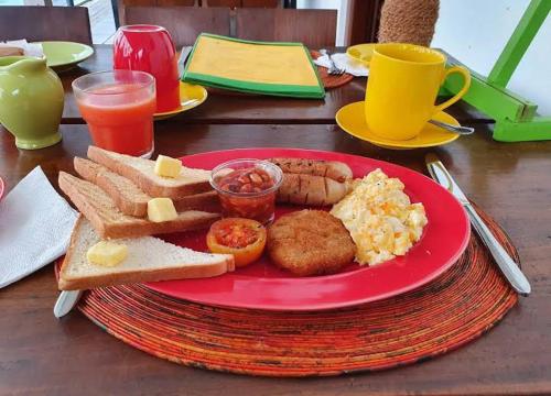 a red plate of breakfast food on a table at Evi's Place in Galle