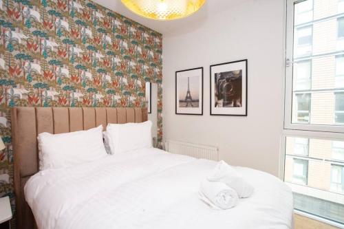 a bedroom with a white bed with a floral wallpaper at Fantastic City Centre Flat in Glasgow