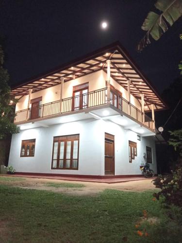 a white house with a balcony at night at Evi's Place in Galle