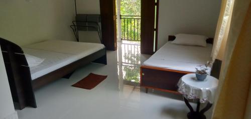 a room with two beds and a window with a table at Evi's Place in Galle
