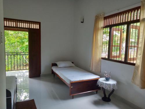 a bedroom with a bed and a table and windows at Evi's Place in Galle