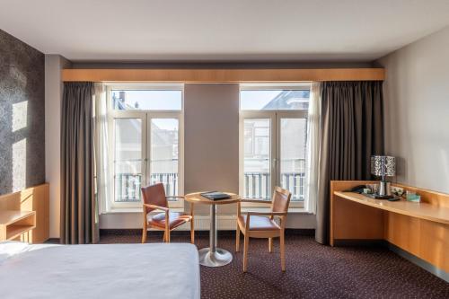 アールスメールにあるHotel Aalsmeerのベッド、テーブル、椅子が備わるホテルルームです。