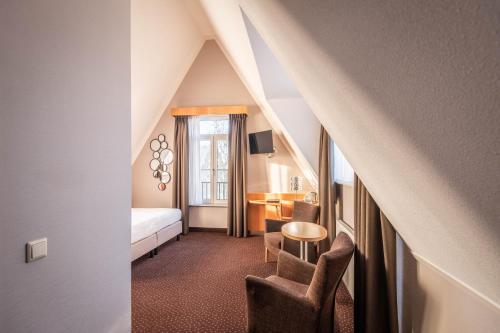 a hotel room with a bed and a table and chairs at Hotel Aalsmeer in Aalsmeer