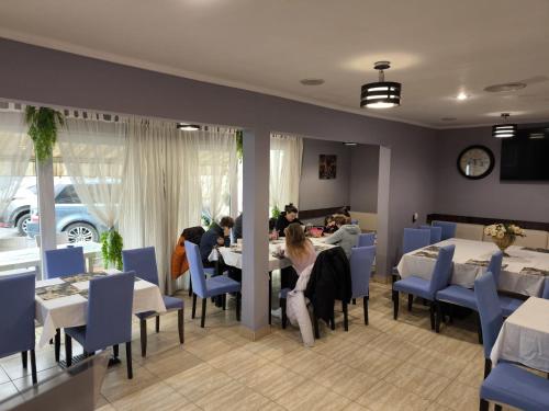 personas sentadas en mesas en un restaurante con sillas azules en Vila Chesa, en Corunca