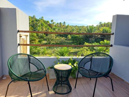 two chairs and a table on a balcony with a view at Pousada Mon Gâté in Japaratinga