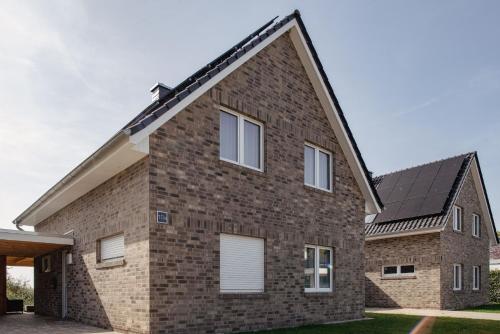 a brick house with a black roof at Haus Willi in Butjadingen