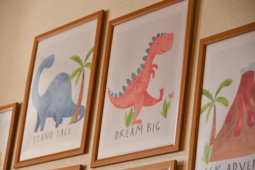 a group of framed pictures of dinosaurs on a wall at かつやま民泊きねん in Katsuyama
